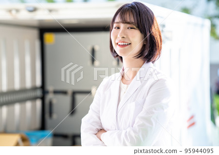 A woman in a white coat standing in front of a truck A woman in a white coat standing in front of a truck 95944095