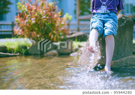 一個快樂的女孩在夏天酷熱的公園裡玩水降溫 一個快樂的女孩在夏天酷熱的公園裡玩水降溫 95944280