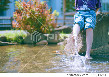 A cheerful girl playing in the water to cool off in a park where the summer heat is harsh A cheerful girl playing in the water to cool off in a park where the summer heat is harsh 95944281