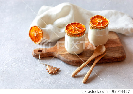 Two portions of yogurt decorated of the dry orange slices 95944497