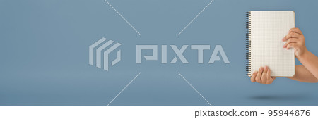 Notepad in hand. Blank notepad in the hands on a blue background. Hands hold a book without text. The girl is holding a book with an empty cover. 95944876