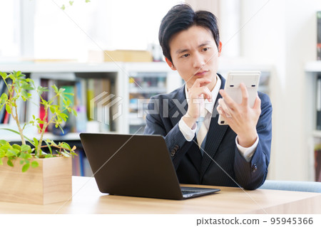 A businessman who worries while looking at a calculator 95945366