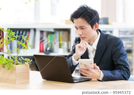 A businessman who worries while looking at a calculator A businessman who worries while looking at a calculator 95945372