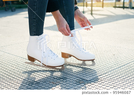 cropped view of woman tying shoe laces on ice skates, banner 95946087