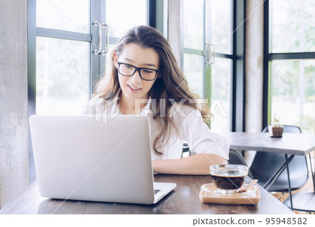 Portrait of young mixed race businesswoman take a coffee break and looking somethings on her laptop in modern office. Conceptual of businesswoman lifestyle. Portrait of young mixed race businesswoman take a coffee break and looking somethings on her laptop in modern office. Conceptual of businesswoman lifestyle. 95948582