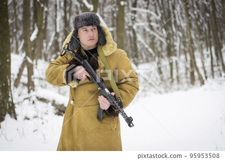 soldier in old coat and fur hat standing with gun in the winter forest 95953508