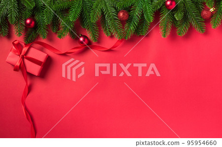 Christmas holiday background with gift box decorations composition, Top view fir green fir tree branches and Xmas ornaments on a red table background 95954660