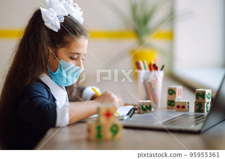 School girl in medical mask using laptop computer studying through online e-learning system. School girl in medical mask using laptop computer studying through online e-learning system. 95955361