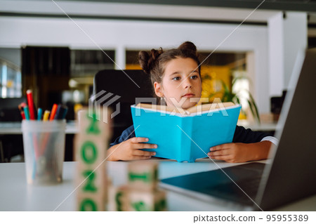 School girl in medical mask using laptop computer studying through online e-learning system. 95955389