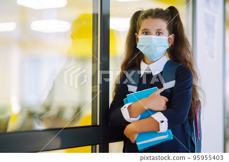Schoolgirl in protective medical mask in school corridor when returning to school during the COVID-19. 95955403