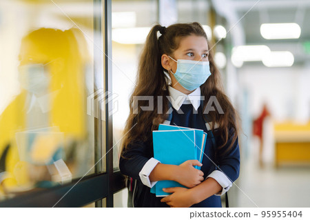 Schoolgirl in protective medical mask in school corridor when returning to school during the COVID-19. 95955404