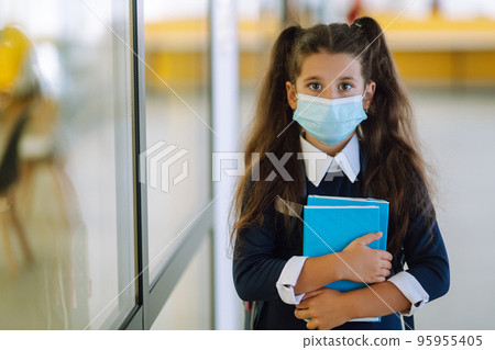 Schoolgirl in protective medical mask in school corridor when returning to school during the COVID-19. 95955405