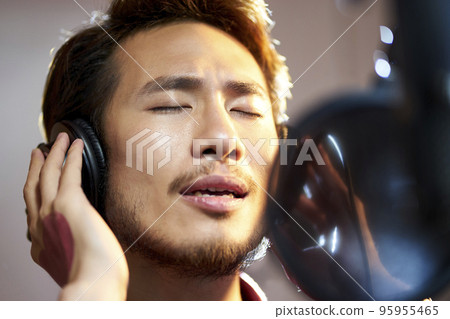 young asian adult man enjoying singing a song in modern recording studio 95955465