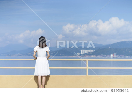 rear view of a young asian woman in white shirt looking at sea 95955641