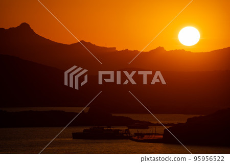 The Sun Falling Behind Mountain peak with sea foreground. A Spectacular golden Sunset  95956522