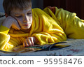 boy lying in bed with a book. child reading home education 95958476