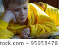 boy lying in bed with a book. child reading home education 95958478