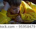boy lying in bed with a book. child reading home education 95958479