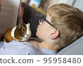 A boy with his guinea pig reading book home education 95958480
