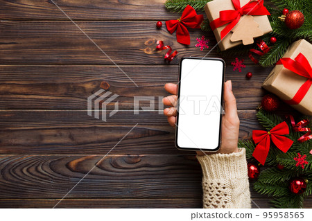 christmas mockup with space for text. christmas advertising, app template. hand holding phone with empty screen on table background. Happy New Year and Xmas Flat lay christmas mockup with space for text. christmas advertising, app template. hand holding phone with empty screen on table background. Happy New Year and Xmas Flat lay 95958565