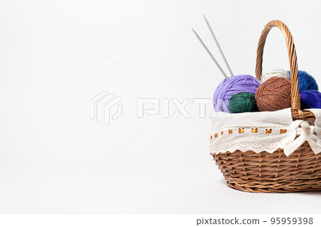 Wicker basket with colored balls of yarn for knitting or crocheting. Hobbies and recreation with needlework. On white background with place for text copy space 95959398
