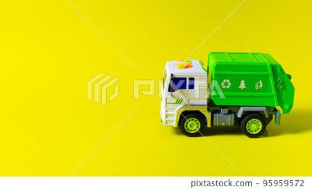 The toy is a garbage truck green with a white body on a yellow background banner with a place for text for a toy store. Children's toys typewriter. 95959572