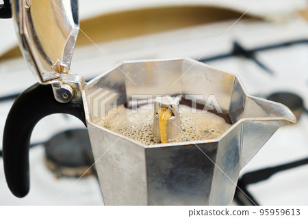 Hot freshly brewed coffee in a geyser coffee maker standing on a gas stove Hot freshly brewed coffee in a geyser coffee maker standing on a gas stove 95959613