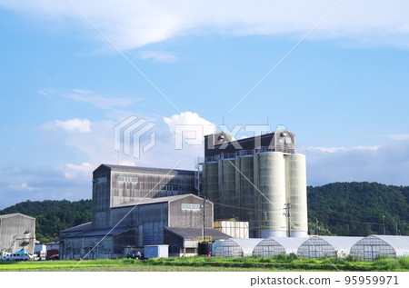 A large building with rice milling equipment standing in the corner of the field 95959971
