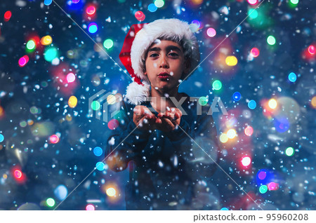 Child with Christmas hat blows to make the snow fly 95960208