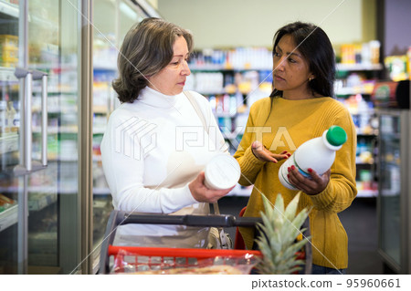 Two female shoppers choosing dairy products in supermarket 95960661