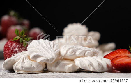 Meringue close up and strawberries in a plate on a black background. Fruit desserts. Meringue close up and strawberries in a plate on a black background. Fruit desserts. 95961397