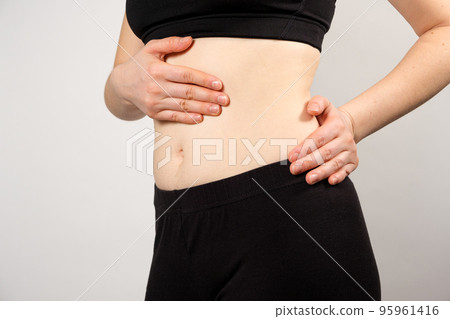 A woman shows the location of the pancreas and spleen, the large intestine. A close-up of the abdomen. 95961416