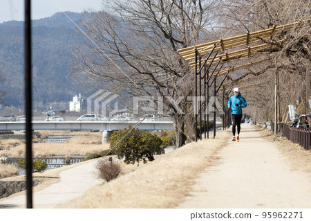 Middle-aged man jogging along the Kamo River in Kyoto in winter Middle-aged man jogging along the Kamo River in Kyoto in winter 95962271