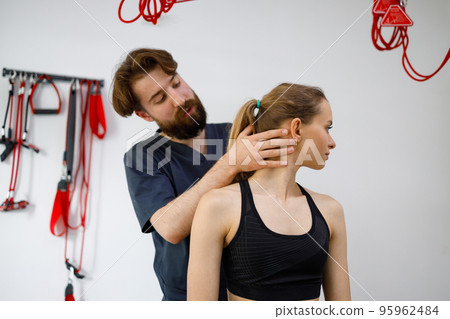 Male orthopedist examining female patient's neck in clinic Male orthopedist examining female patient's neck in clinic 95962484