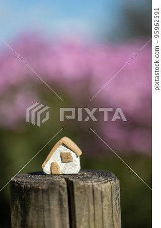 Small cute unglazed pottery house with pink cosmos background 95962591