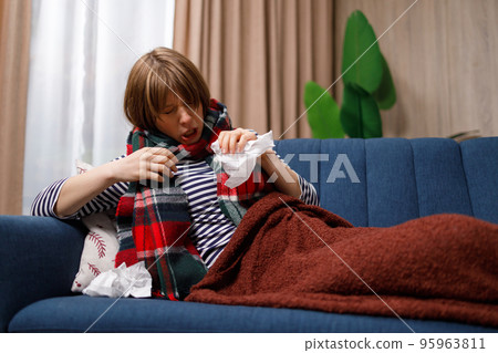 Flu sick young woman sneezes while lying on sofa 95963811