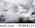 A landscape of the Dolomites Mountain Range covered in the fog under a cloudy sky in Italy 95964114