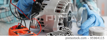 Handyman in gloves repairing automobile part and measuring voltage 95964115