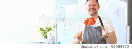 Smiling male cook catching flying red bell pepper Smiling male cook catching flying red bell pepper 95964160