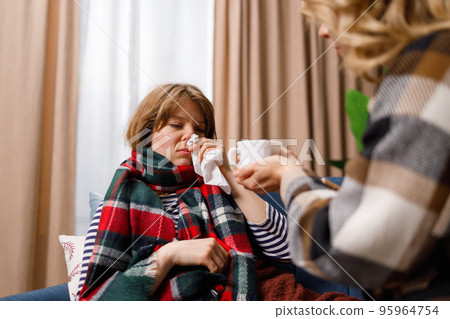 Woman takes care of her daughter who has the flu gives her hot tea to drink 95964754