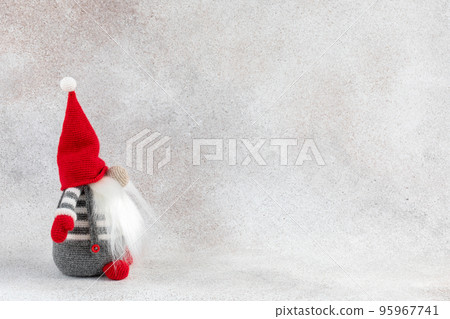 Christmas handmade gnome in red hat side view holiday banner on light winter background Christmas handmade gnome in red hat side view holiday banner on light winter background 95967741