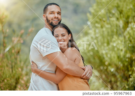 Black couple, hug and smile in woods together, outdoor and bush with love, romance or bonding on vacation in nature. Happy, man and woman embrace in portrait, forest or trees for happiness 95967963
