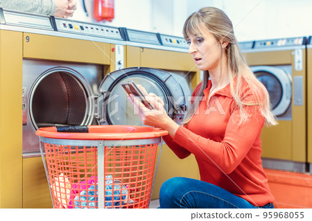 Woman finds mobile phone in laundry basket Woman finds mobile phone in laundry basket 95968055