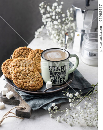 Mug of hot coffee with homemade oatmeal cookies on a rustic metal tray. Home warmth and comfort in autumn morning concept. Autumn still life 95968457