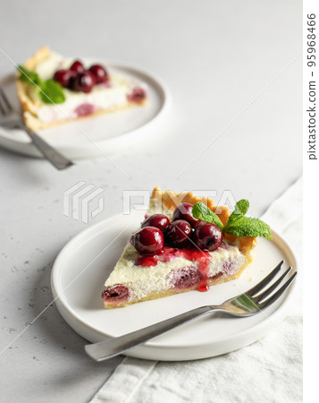 Portion of cottage cheese casserole or pudding with cherry and mint leaveson white background. Cherry cheesecake 95968466