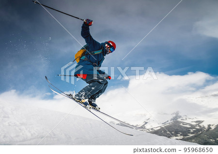 male skier jumping from mountain creating snow plume, winter extreme sport, downhill skiing 95968650