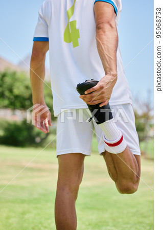 Soccer, sports and athlete stretching his leg before a match, training or practice on an outdoor field. Football, workout and man doing a warm up exercise for game or workout on a pitch at a stadium. 95968758
