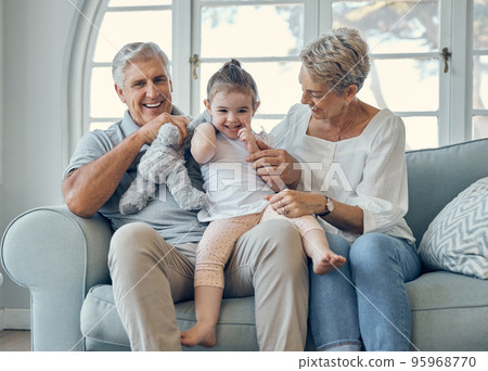 Family, grandmother and grandfather with girl on sofa, having fun and bonding. Portrait, love and care of happy grandparents with kid or child on couch in living room enjoying quality time together. Family, grandmother and grandfather with girl on sofa, having fun and bonding. Portrait, love and care of happy grandparents with kid or child on couch in living room enjoying quality time together. 95968770
