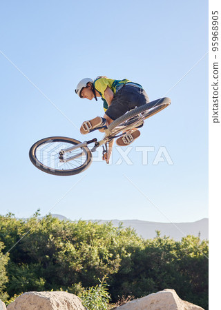 Bike, extreme sport and outdoor fitness, man does dangerous stunt, sports motivation and training in nature. Exercise, athlete with mountain bike, risk and active with energy and jump over rocks. Bike, extreme sport and outdoor fitness, man does dangerous stunt, sports motivation and training in nature. Exercise, athlete with mountain bike, risk and active with energy and jump over rocks. 95968905
