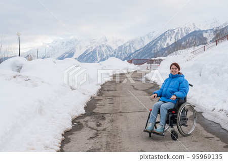 Caucasian woman in a wheelchair travels in the mountains in winter. Caucasian woman in a wheelchair travels in the mountains in winter. 95969135